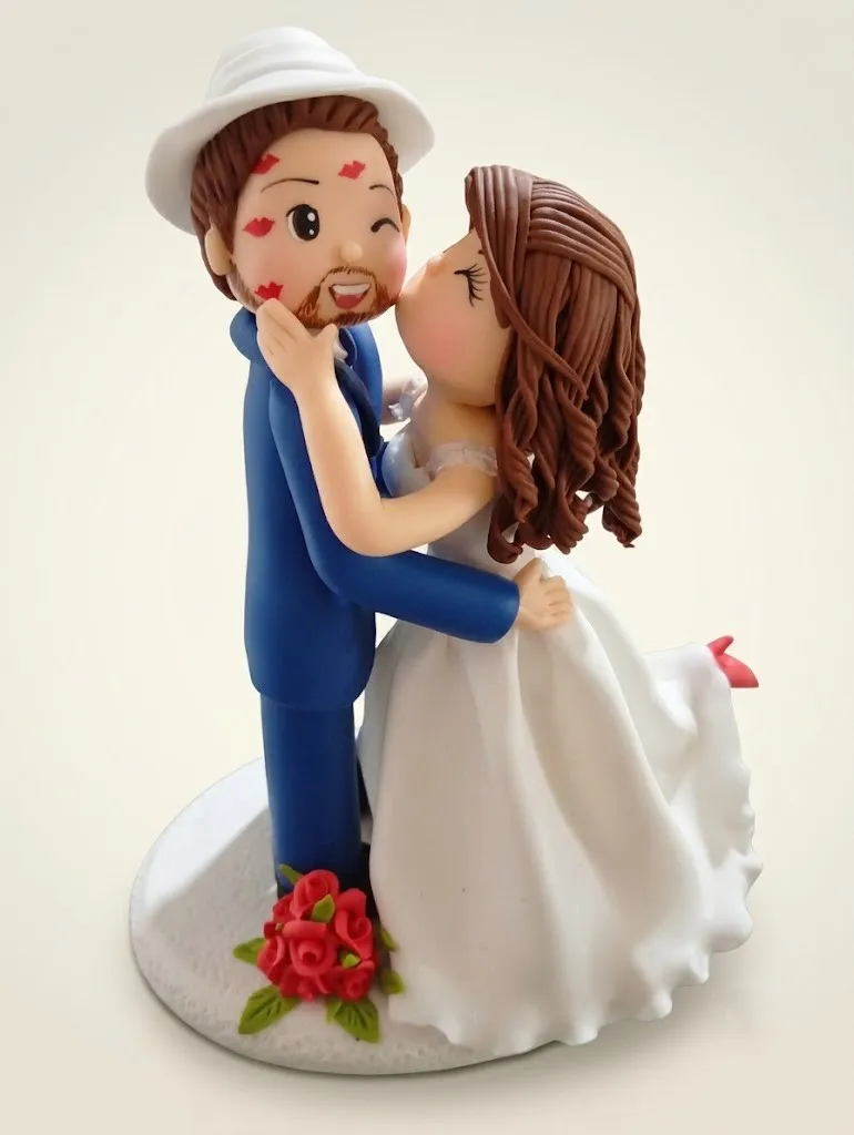 Novio con sombrero y la cara llena de besos, mientras la novia lo besa en la mejilla