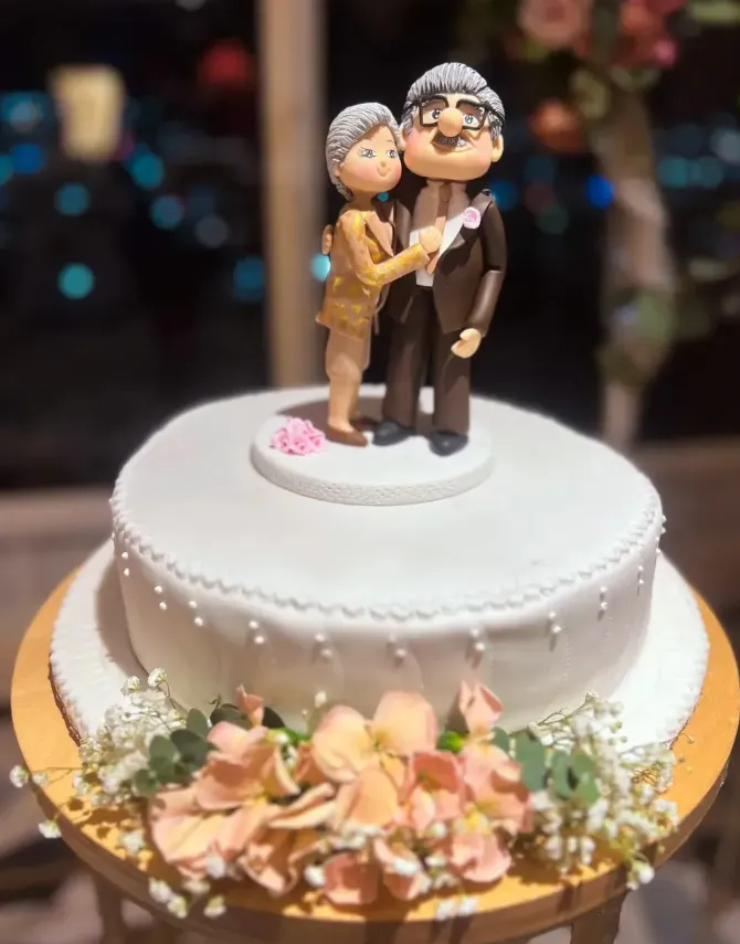 Pareja de esposos mayores coronando una torta blanca de aniversario